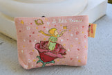 Small pink  makeup, toiletries pouch with Le Petit prince design on a light surface;  little prince pouch le petit prince gift