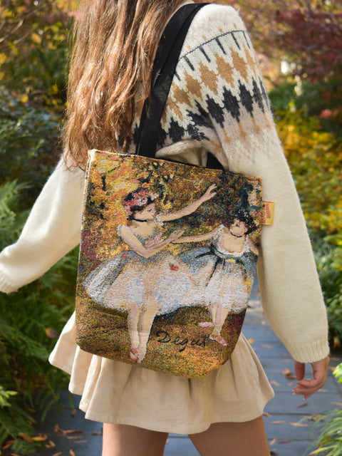 Person wearing a bag with a classical dance painting design outdoors