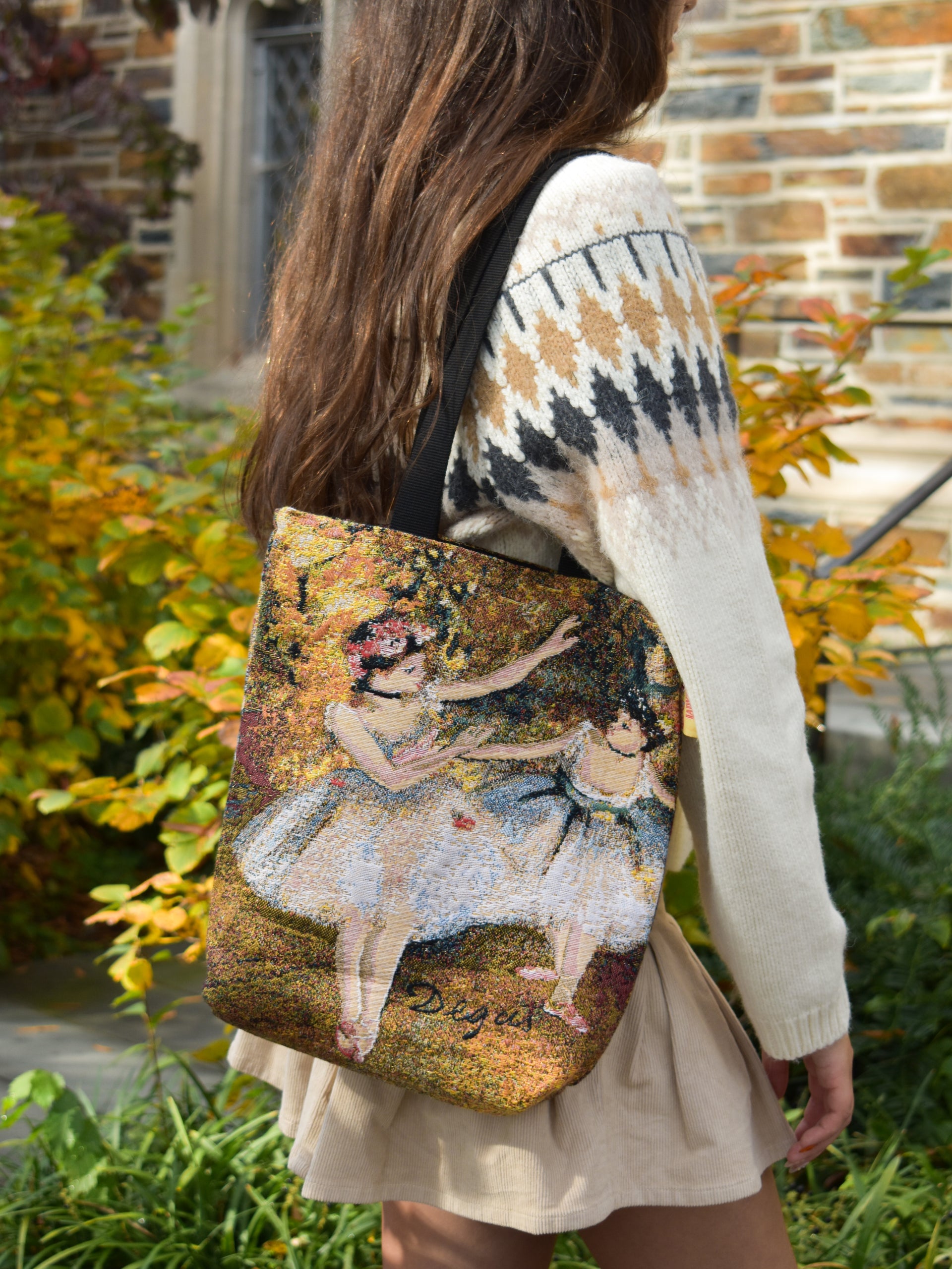 Person wearing a tote bag with an Edgar Degas painting design outdoors.