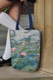 Person holding a Monet floral water lilies tote bag against a stone wall.