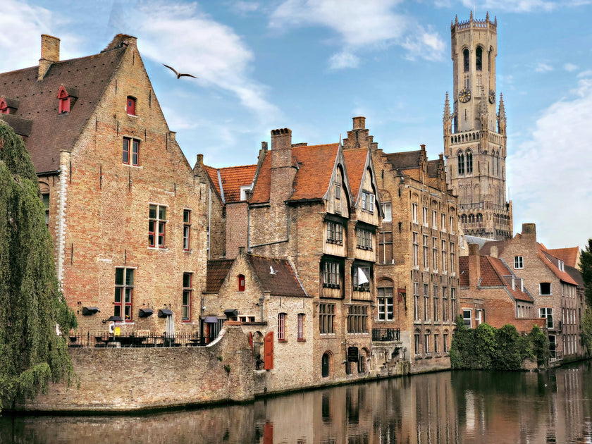 Historic canal scene with brick buildings and a clock tower in Bruges, Belgium.