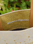 Gold glittery label with 'Woven in Flanders' text on a fabric background