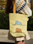 Person holding a tote bag with animal illustrations outdoors