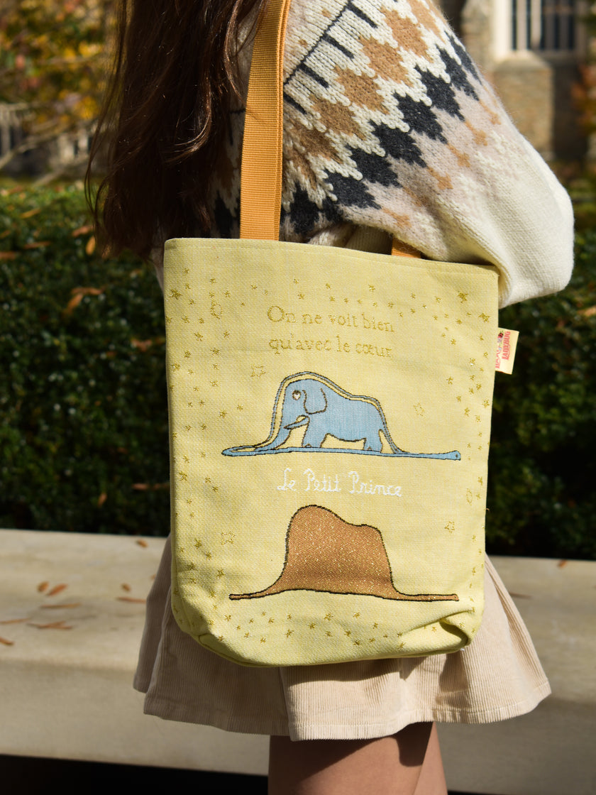 Person holding a tote bag with animal illustrations outdoors