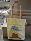 Tote bag with an elephant design and text, placed on a stone surface.