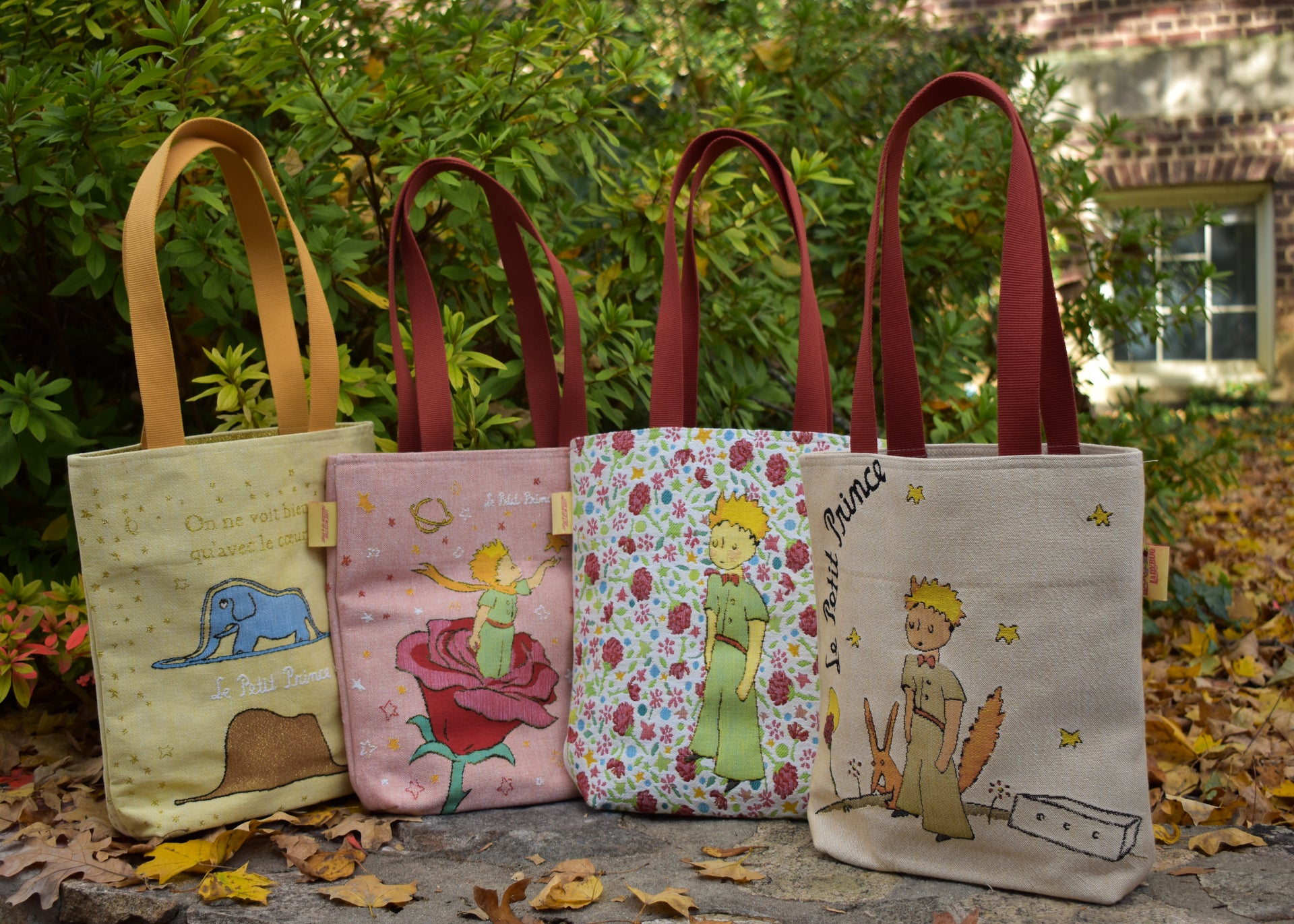 Four tote bags with different designs on a leafy background