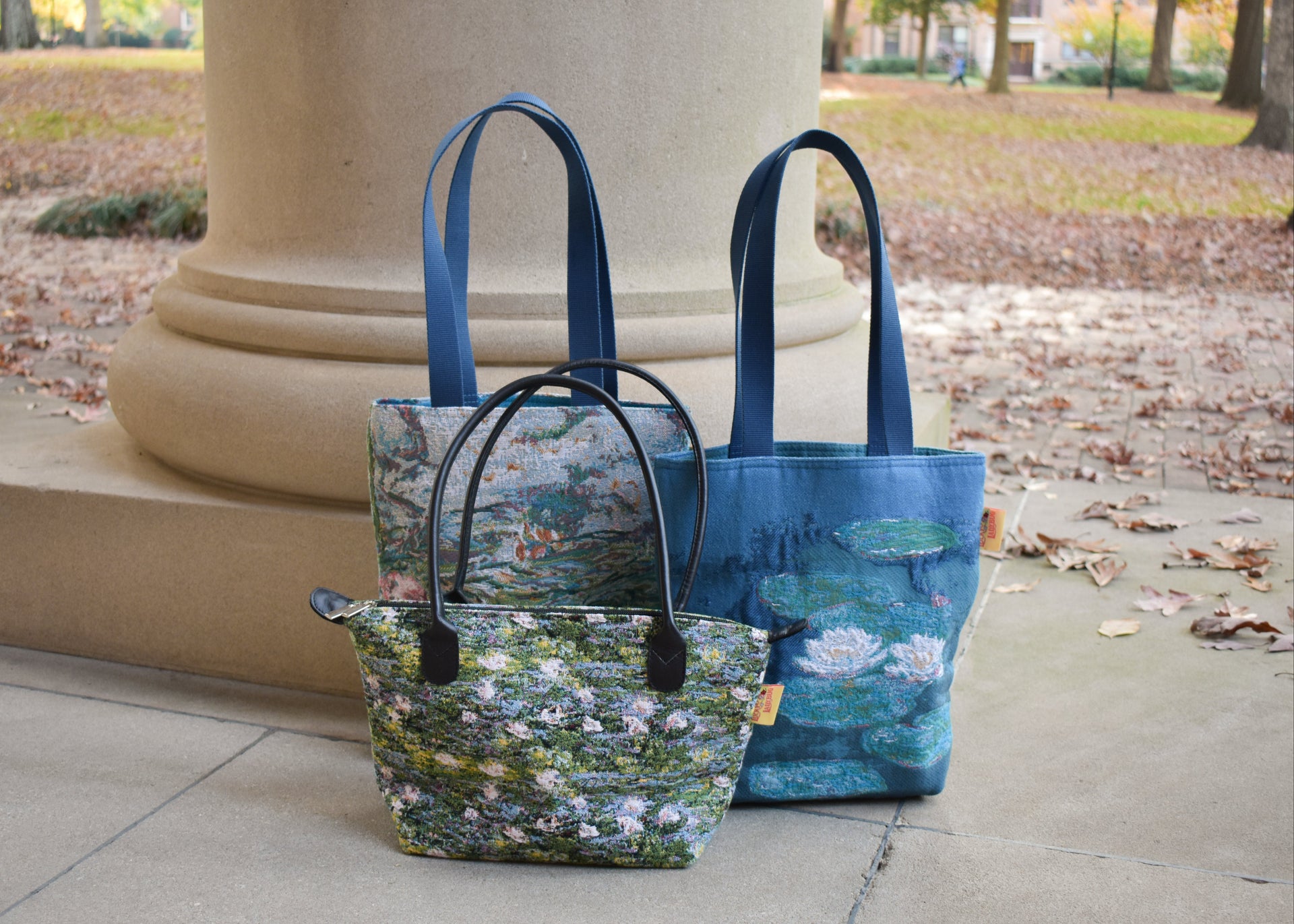 Two tote bags with floral designs on a stone surface outdoors.